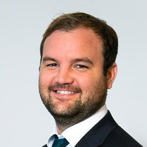 Man wearing a suit and tie against a plain background