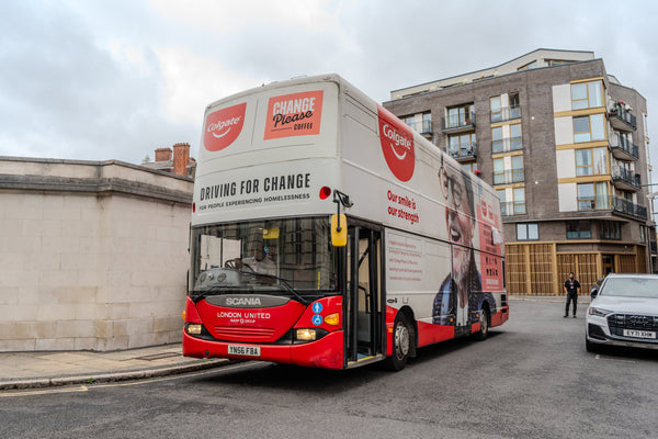 Double-decker bus with Colgate and Change Please branding.