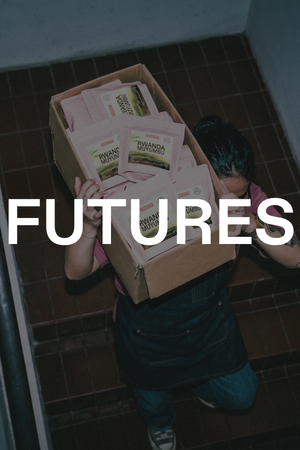 Person holding a box of coffee products on a tiled floor, with words 'Futures' overlayed