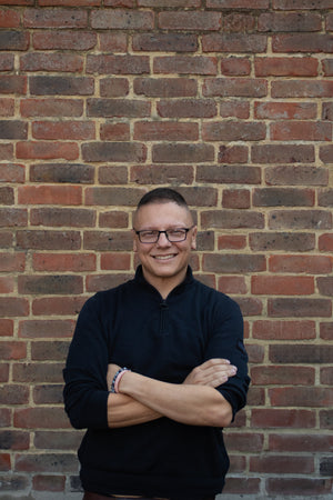 man standing in black shirt against a brick wall 